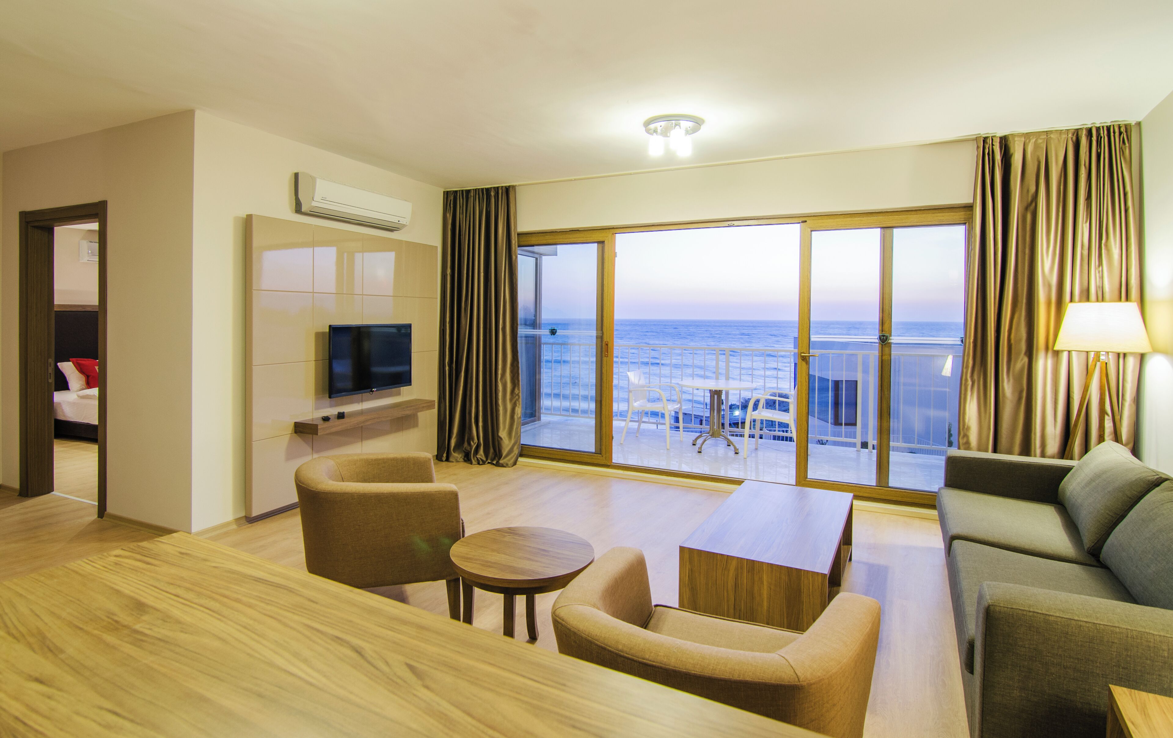 Une chambre d’hôtel avec un balcon, une télévision, un canapé, une table et une chaise.