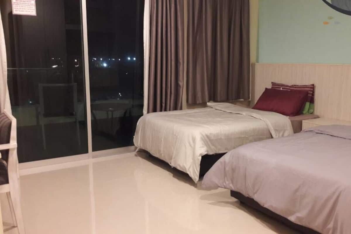 Ein Hotelzimmer mit zwei Betten, einer Schiebetür zu einem Balkon und einem Wandgemälde.