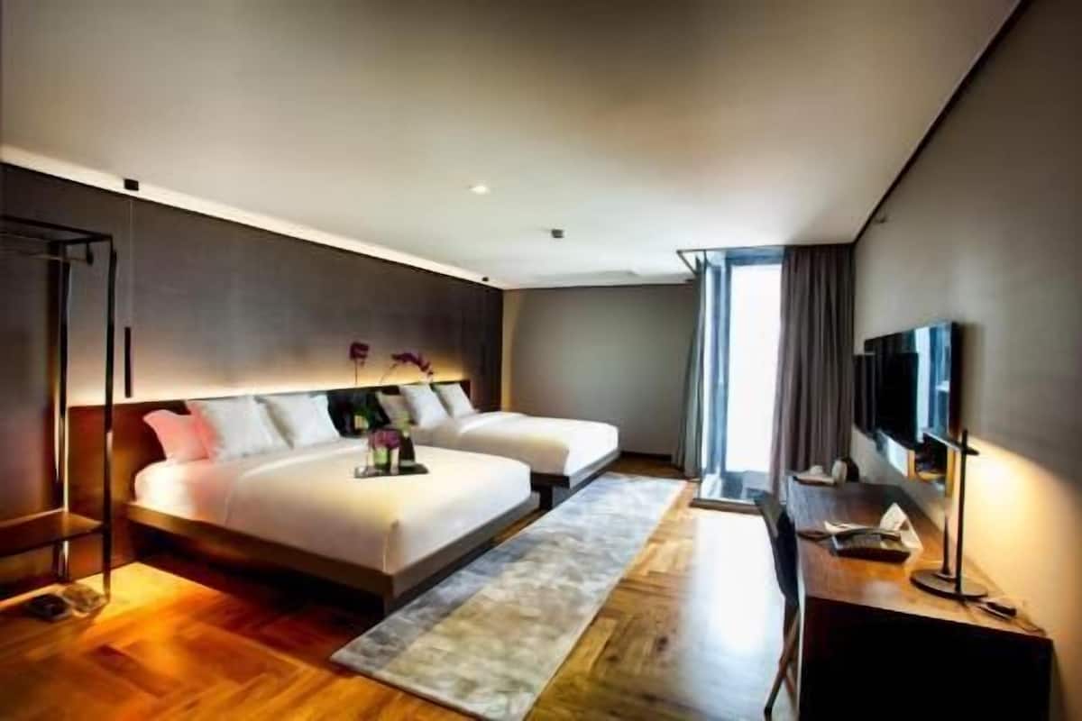 Una habitación de hotel moderna con una cama grande, un escritorio, un televisor de pantalla plana y un ventanal amplio.