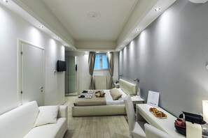 Una habitación de hotel moderna con cama, sofá, una mesita y un escritorio.