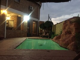 Una piscina al aire libre, sombrillas, sillones reclinables de piscina