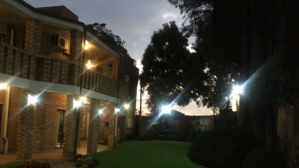 A building with a brick facade, multiple balconies, and a well-maintained lawn.