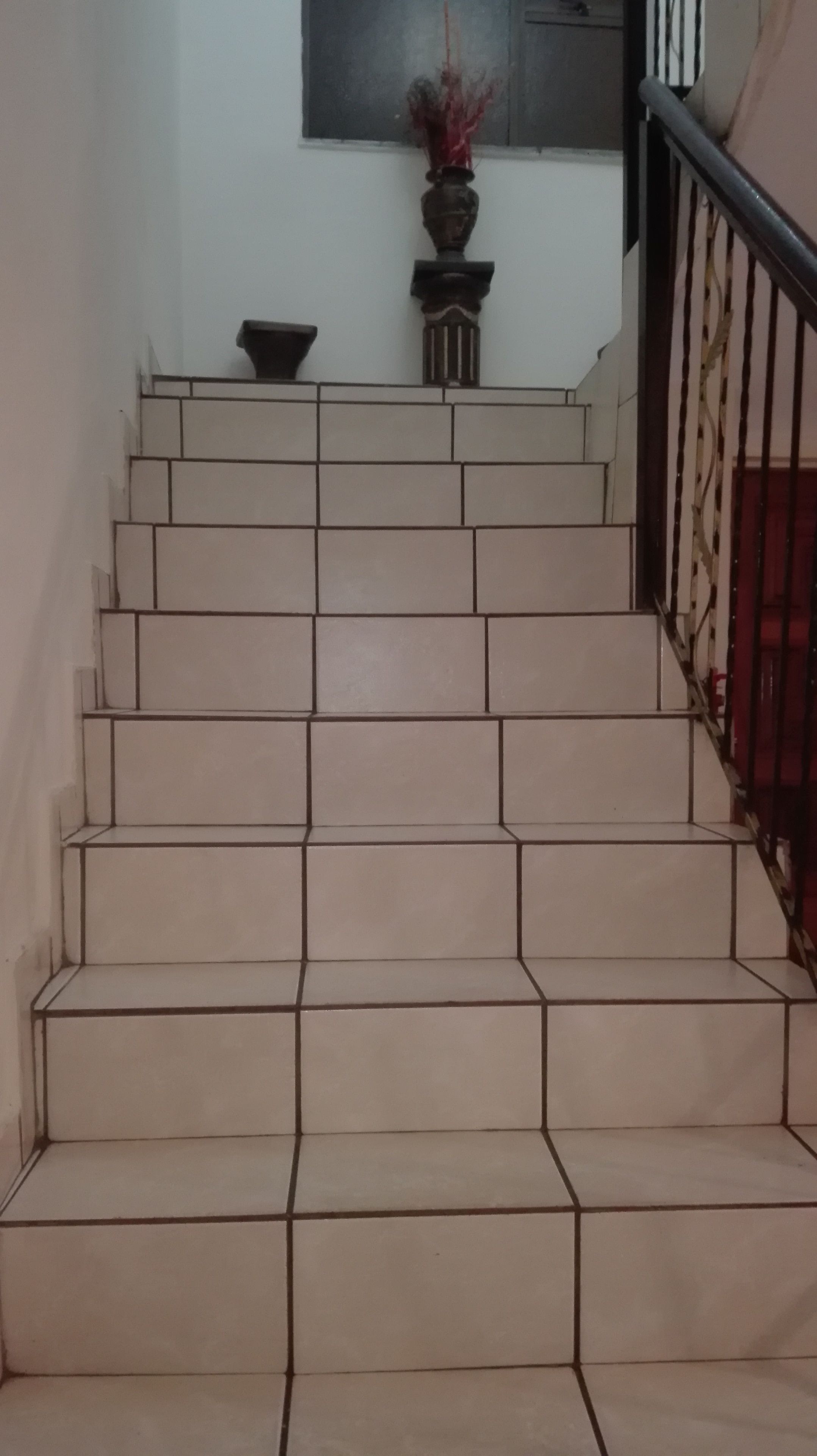 A staircase with beige tiles and a black railing.