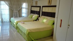 A hotel room with two beds, each with green bedding and white headboards.