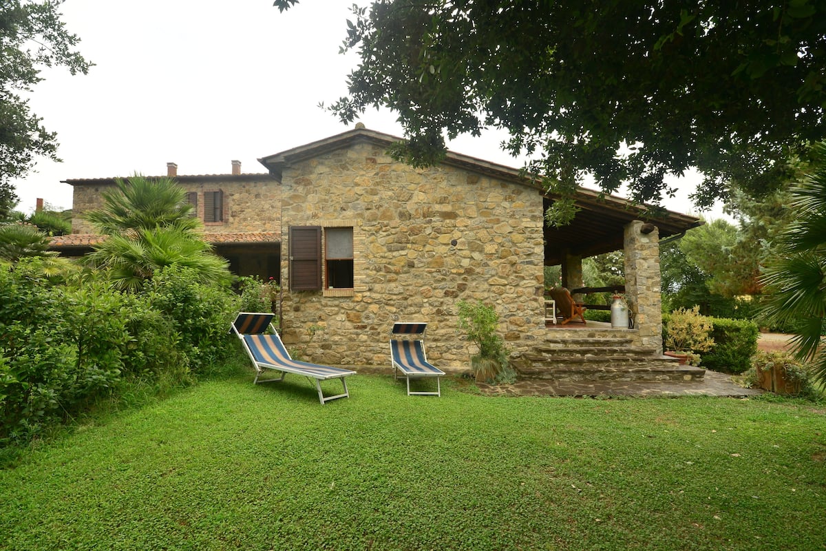 Ein Steinhhaus mit überdachter Veranda und zwei Liegestühlen.
