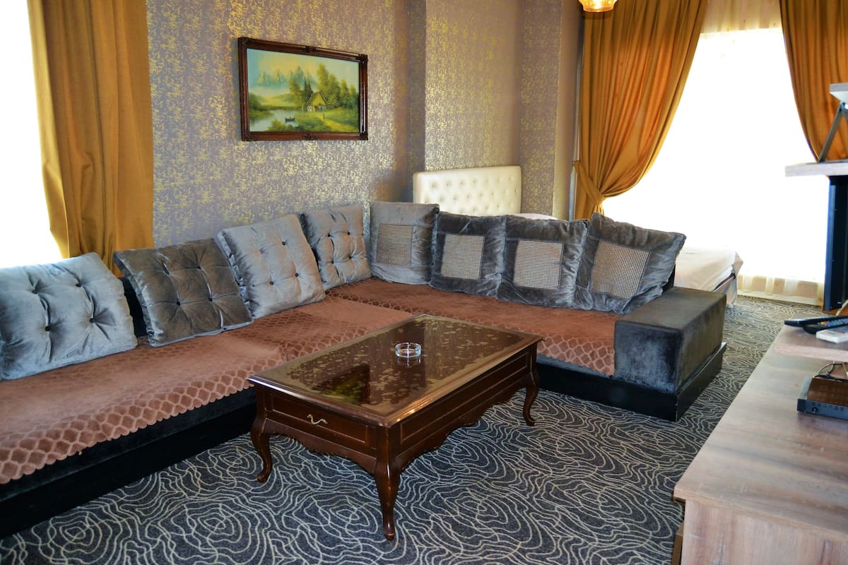 Una sala de estar con un sofá modular, una mesa de centro de vidrio y un televisor.