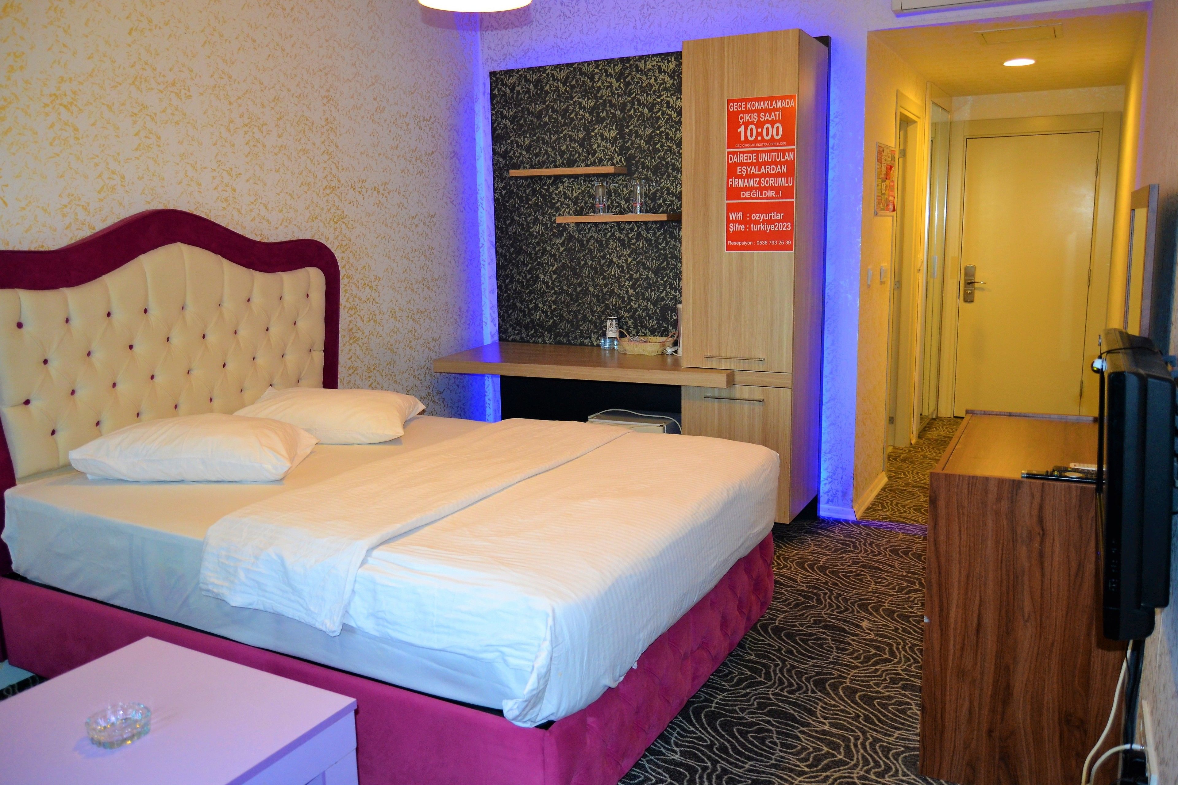 Une chambre d’hôtel avec un lit, un bureau, un miroir et une porte.