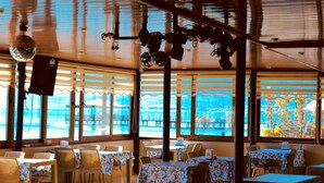 A restaurant with tables and chairs, large windows, and a disco ball. - Bonita Hotel (Edremit)