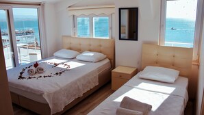 A hotel room with a bed, a nightstand, and a view of the sea. - Bonita Hotel (Edremit)