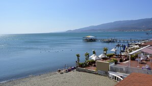 A coastal area with a beach, a pier, and a restaurant with outdoor seating. - Bonita Hotel (Edremit)