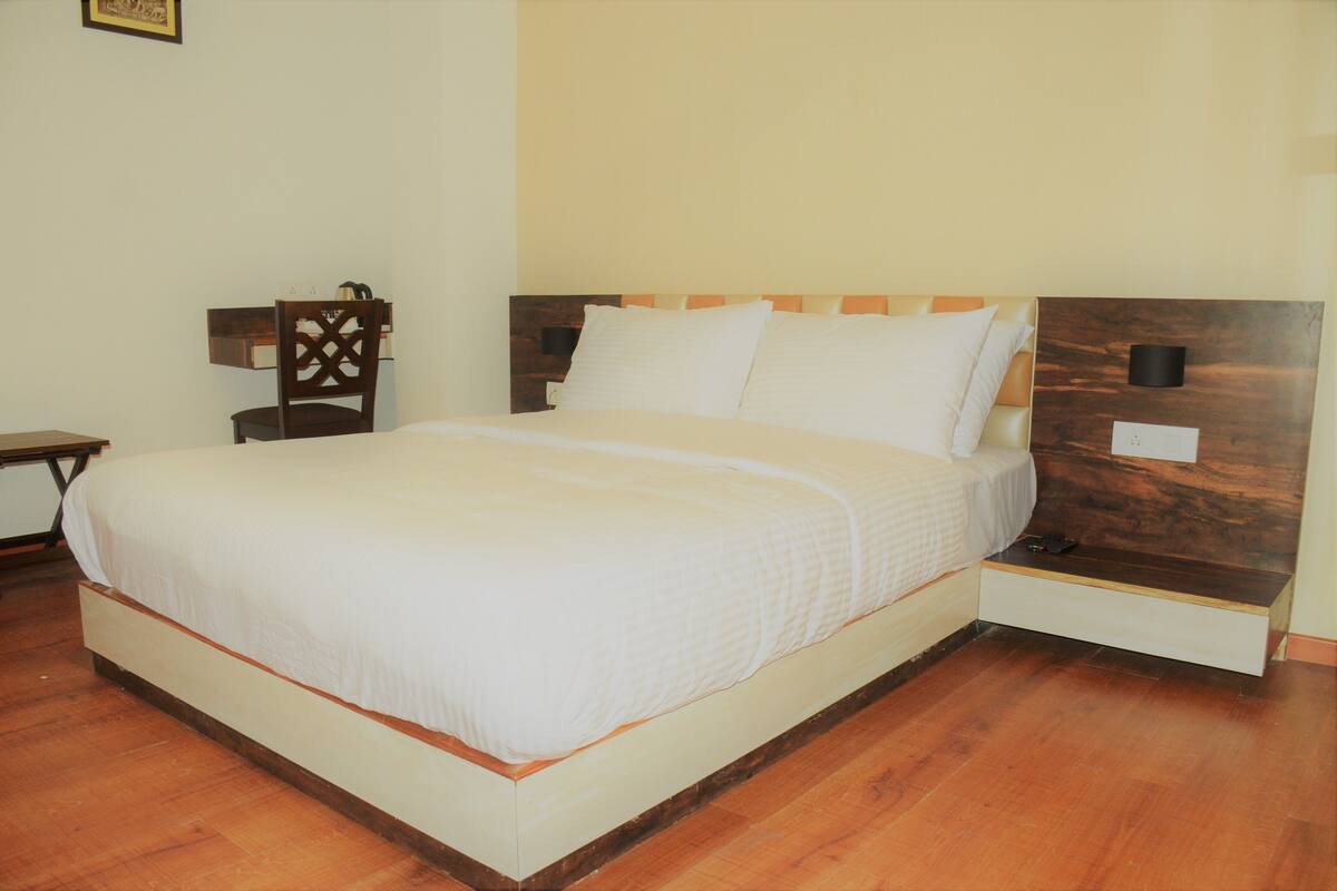A neatly made bed with a wooden headboard, a bedside table with a lamp, and a chair.