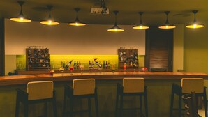 A bar area with a wooden counter, four bar stools, and overhead pendant lighting. - Hotel Aura (Shillong)