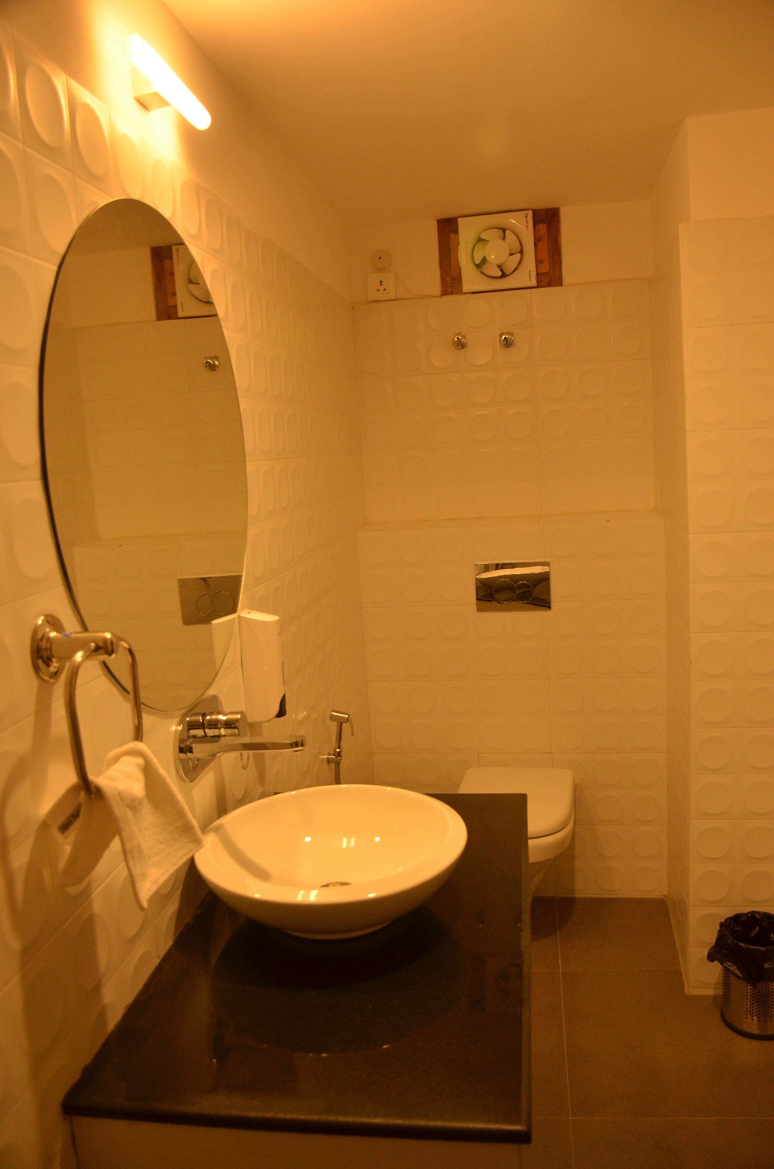 Un baño con lavamanos, espejo e inodoro blancos.