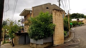 A residential street with houses, a curved road, and a parked car. - Green flower hotel (Kutaisi)