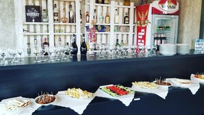 A bar area with a variety of liquor bottles and glasses, and a buffet with several food options. - Green flower hotel (Kutaisi)