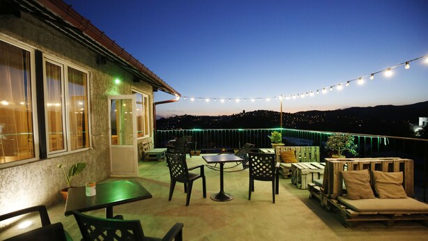 An outdoor patio with a table and chairs, a sofa, and string lights. - Green flower hotel (Kutaisi)