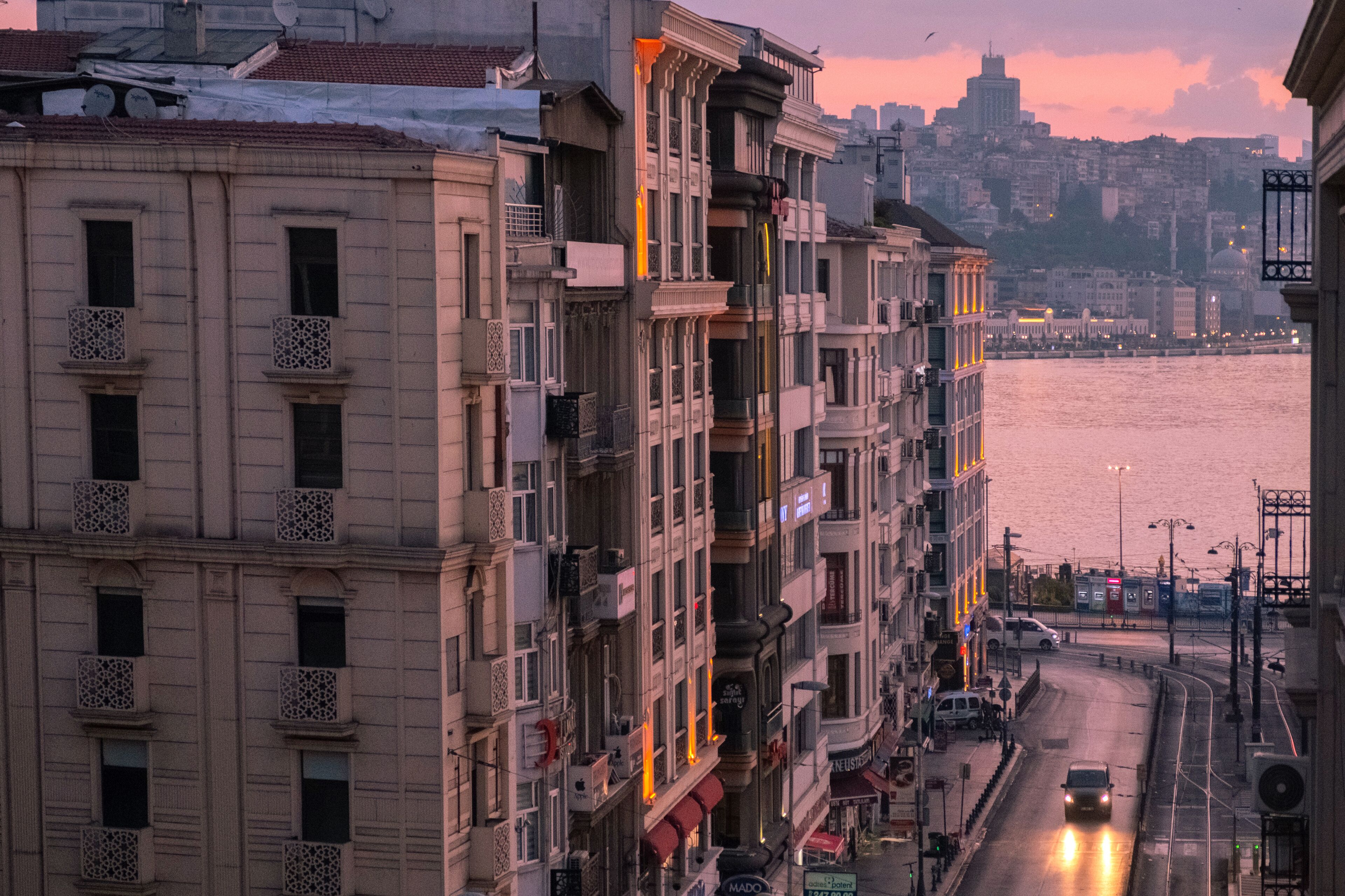Un immeuble à plusieurs étages doté de balcons, avec une rivière en arrière-plan et une vue sur la ville.