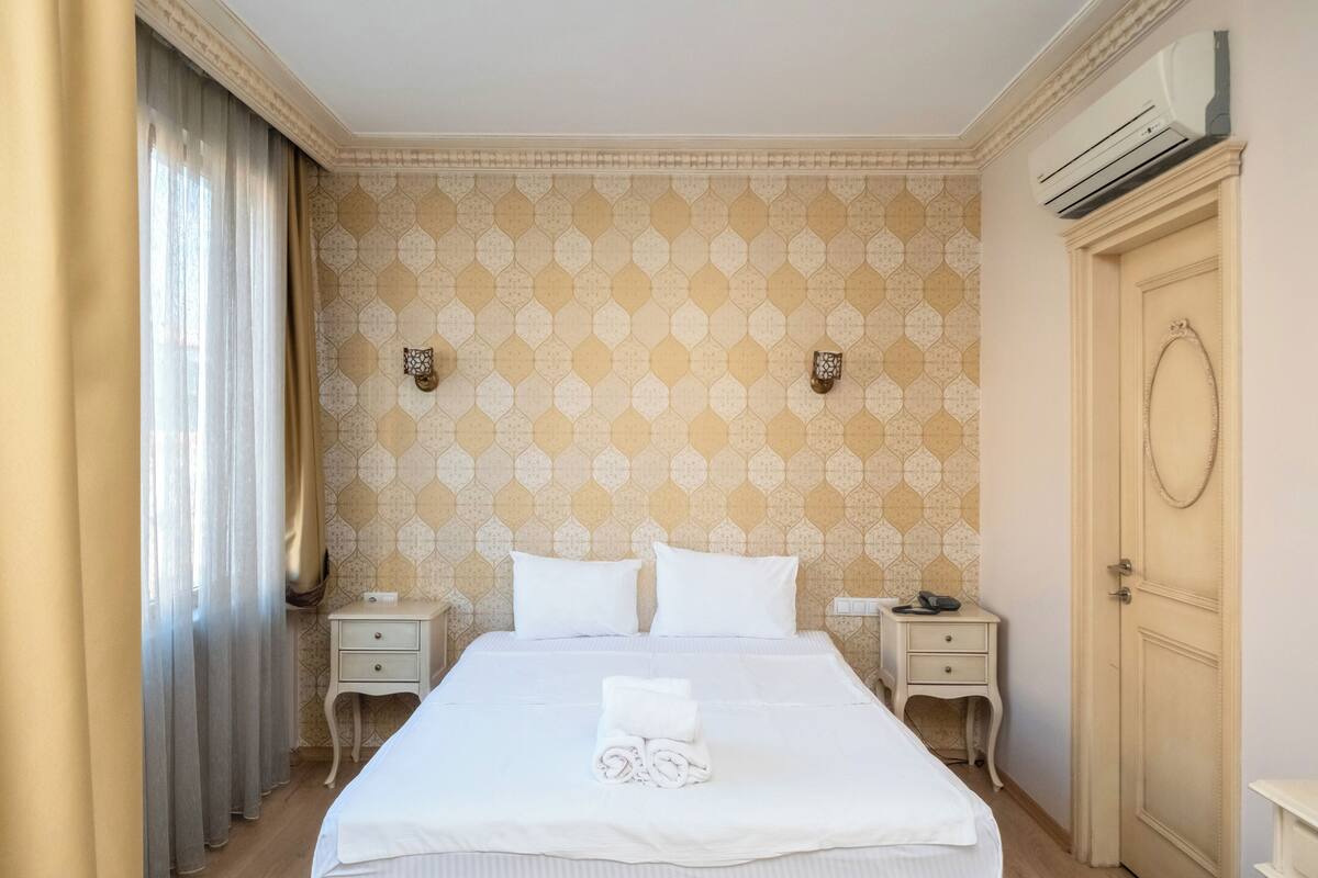 Ein Hotelzimmer mit einem großen Bett, zwei Nachttischen, einem Kleiderschrank und einer Klimaanlage.