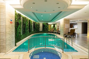 An indoor swimming pool with a tiled floor, a metal railing, and a green wall with plants. - Felicity Hotel Istanbul  (Istanbul)