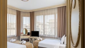 A hotel room with two beds, a desk with a television, a mirror, and a view of the city through large windows. - Felicity Hotel Istanbul  (Istanbul)