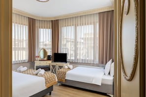 A hotel room with two beds, a desk with a television, a mirror, and a view of the city through large windows. - Felicity Hotel Istanbul  (Istanbul)