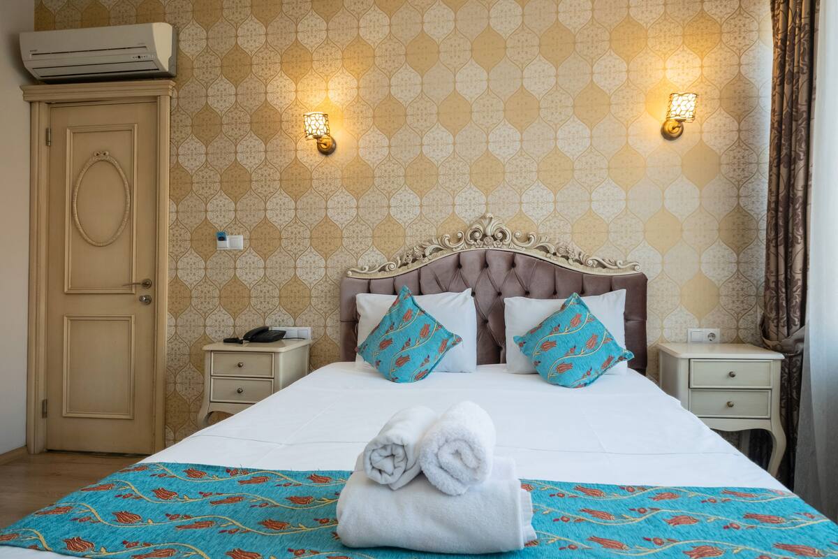 Ein Hotelzimmer mit einem großen Bett, zwei Nachttischen, einem Kleiderschrank und gestreifter Tapete.