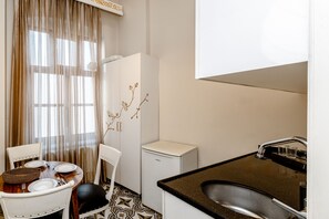 A compact kitchen with a dining area, a small refrigerator, and a sink. - Felicity Hotel Istanbul  (Istanbul)