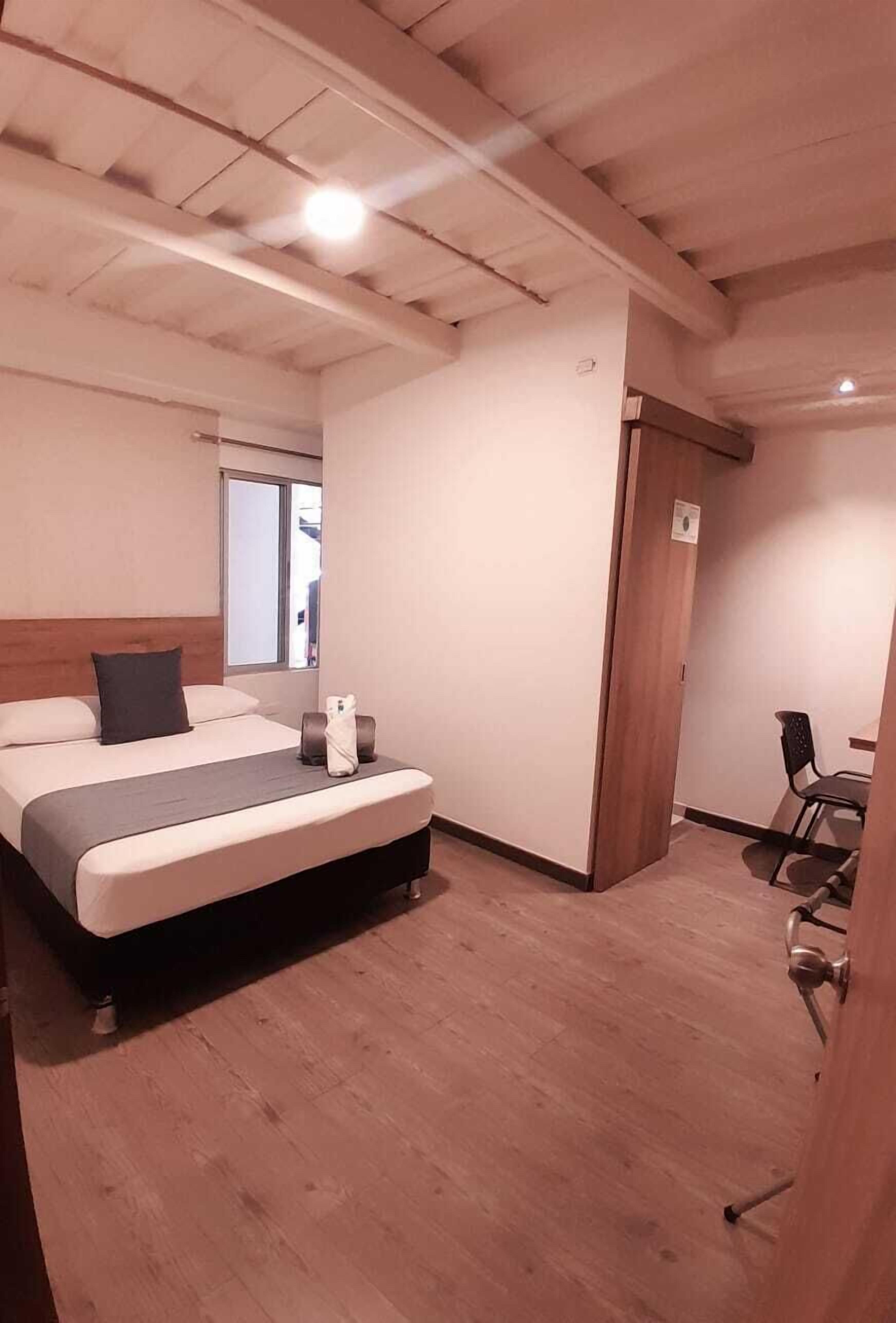 Una habitación de hotel con una cama, un escritorio y una silla.