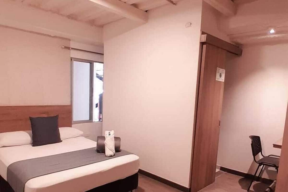 Una habitación de hotel con una cama, un escritorio y una silla.
