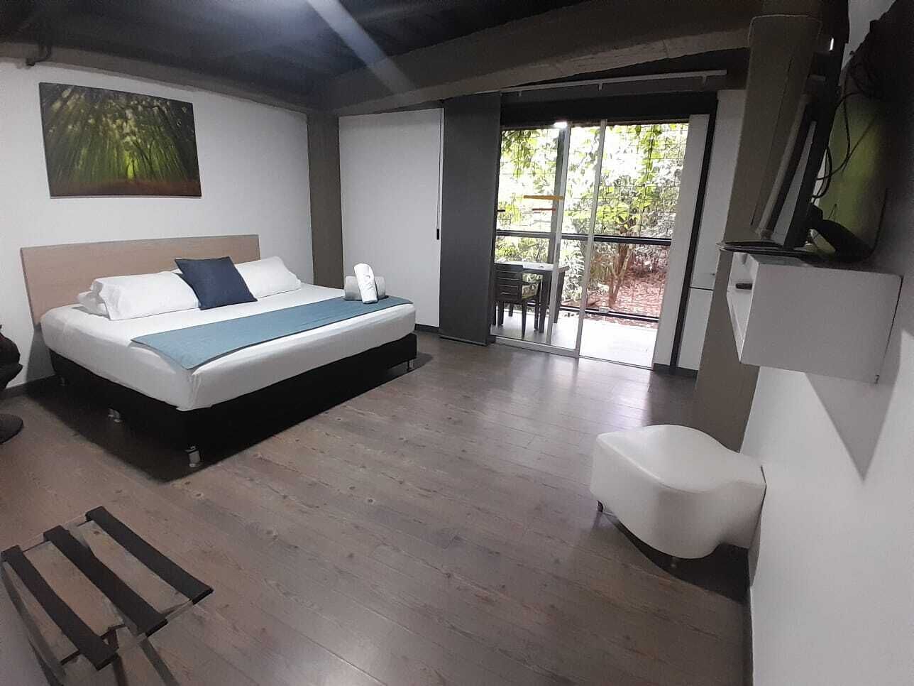 Un dormitorio con cama, una silla, un escritorio, una ventana y una puerta que da a un balcón.