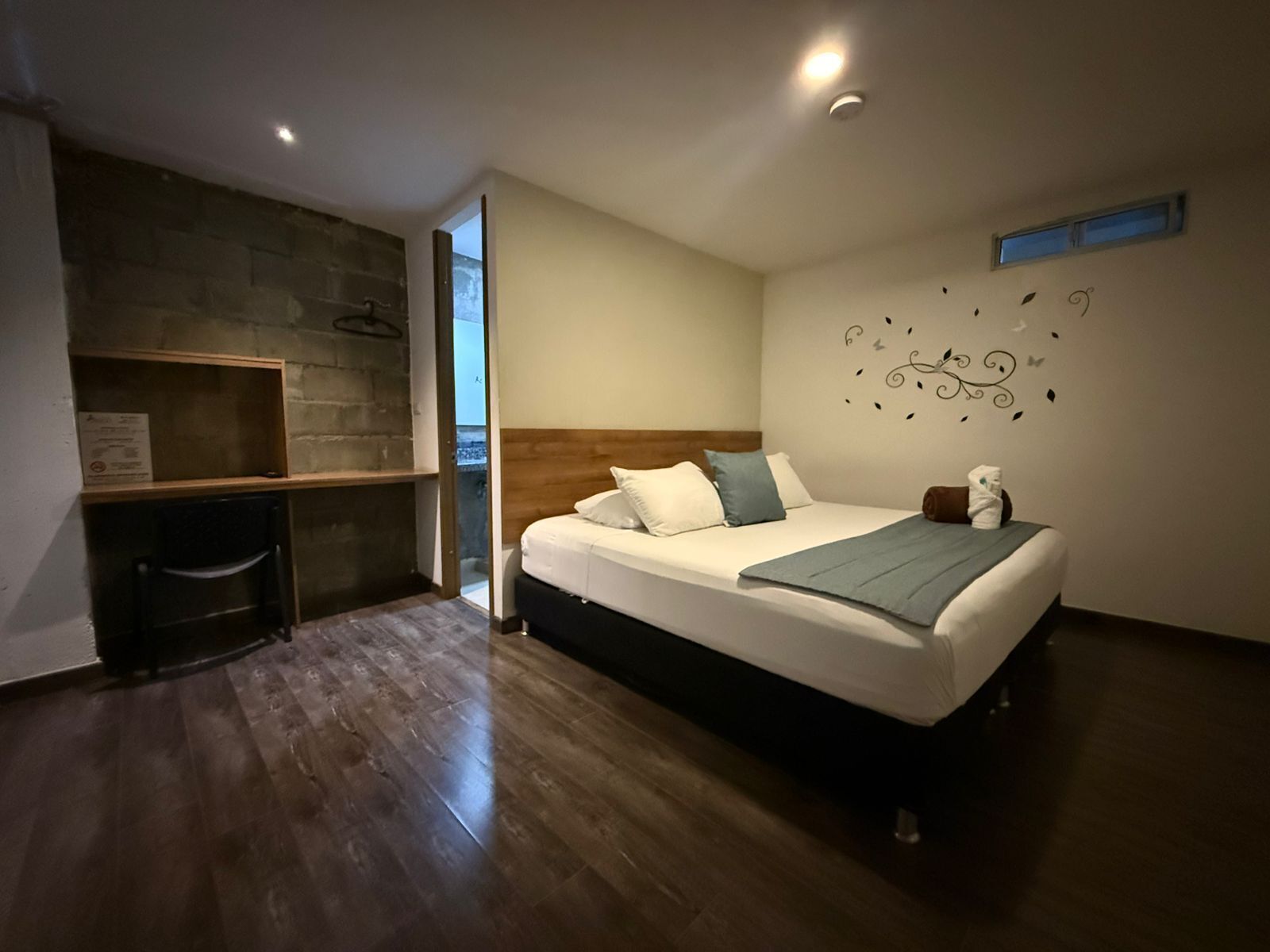 Un dormitorio con una cama, un escritorio de madera, una pared de piedra y un adhesivo decorativo.