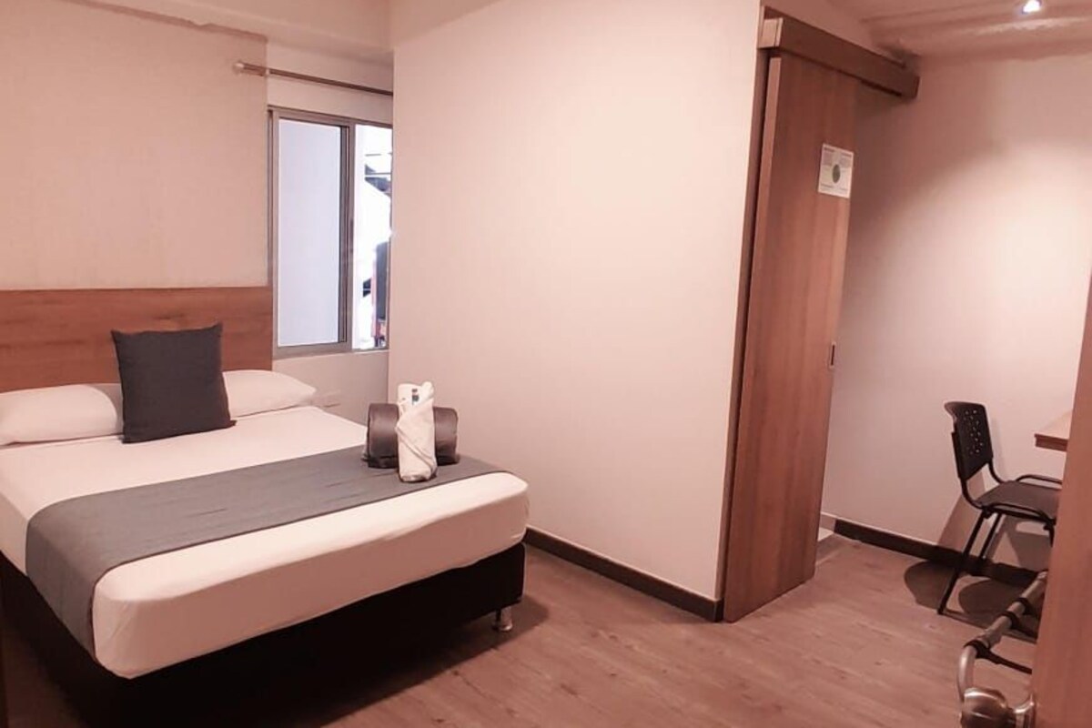 A hotel room with a bed, a desk, and a chair.