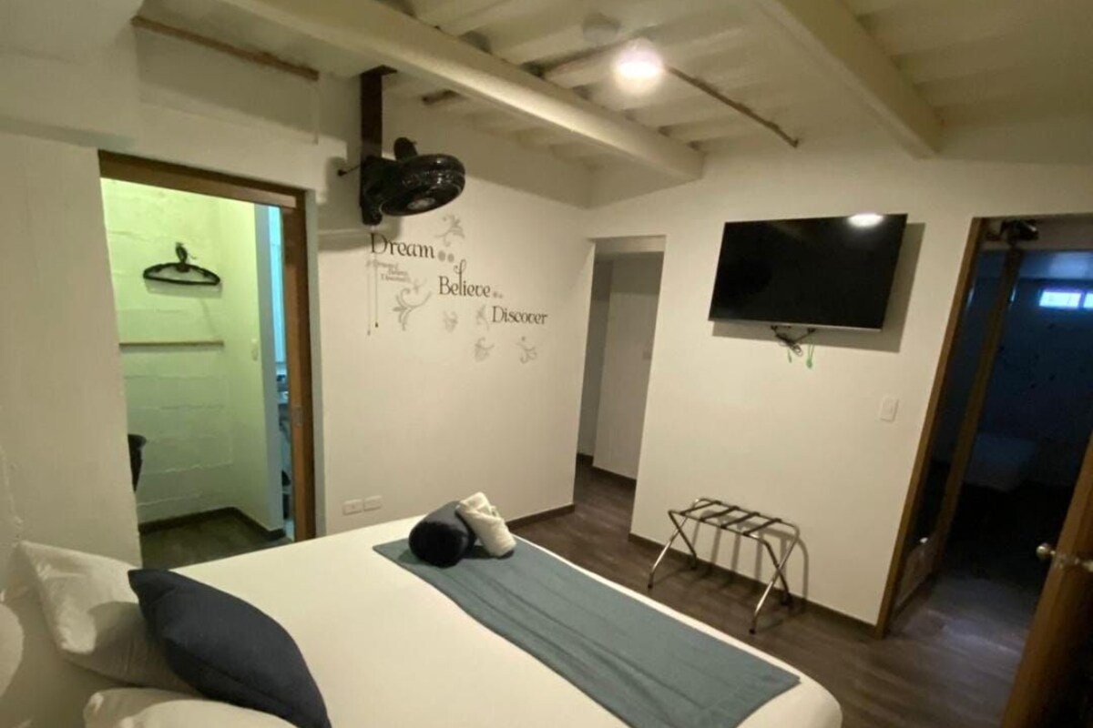 A bedroom with a bed, pillows, a wall-mounted TV, and a motivational quote.