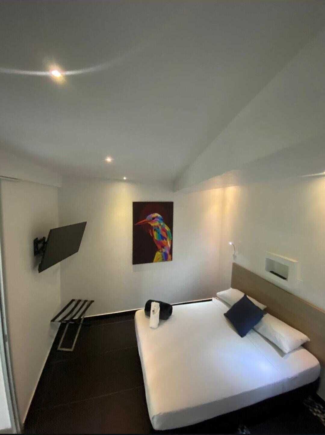 Una habitación de hotel moderna con una cama, un cuadro, un escritorio y una silla.