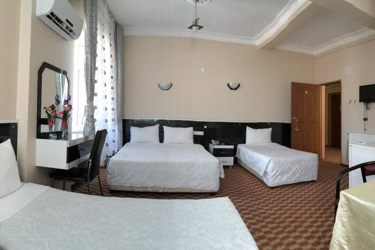 Habitación de hotel con dos camas, un escritorio, una silla, un televisor y un cuadro en la pared.