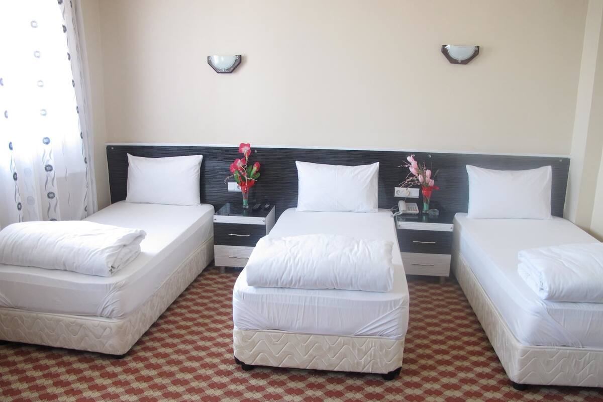 Habitación de hotel con dos camas, piso a cuadros y una lámpara fijada a la pared.