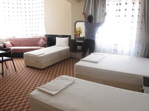 A hotel room with two beds, a sofa, a desk, and a chair.