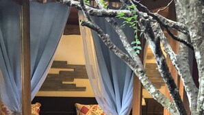 A room with two beds, each covered with patterned blankets and pillows. The room has a wooden floor and a small table with a tablecloth. - Casa Carmel (Búzios)