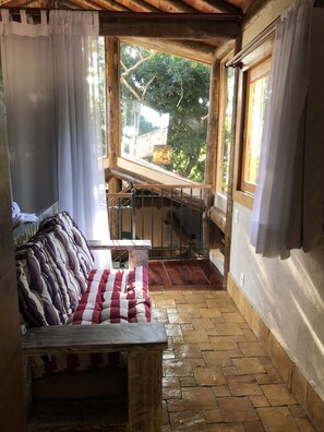 Een gezellige kamer met een houten bankje, een kleine tafel en uitzicht op een trap die naar buiten leidt.