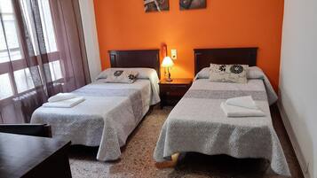 Ein Hotelzimmer mit zwei Betten, einem Nachttisch mit Lampe und einem Kunstwerk an der Wand.
