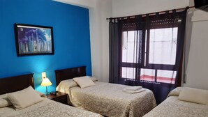 Camera d'albergo con due letti, un comodino con una lampada, un quadro appeso al muro e una finestra con tende.