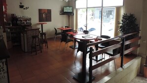 Un caffè con un'area bar, tavoli, sedie e una grande vetrata.