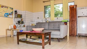 A compact living space with a sofa, a coffee table, a map on the wall, and a kitchen area with a refrigerator and microwave. - Macsapartment (Paramaribo)