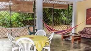 A patio area with a table and chairs, a hammock, and a sofa. - Macsapartment (Paramaribo)