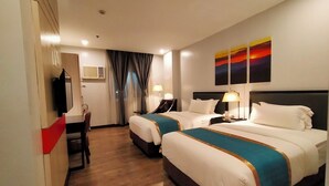 A hotel room with two beds, a desk, a TV, and a painting on the wall. - Studio 89 Katipunan QC (Quezon City)