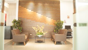A reception area with a wooden slat wall, two armchairs, a coffee table with a floral arrangement, and potted plants. - Studio 89 Katipunan QC (Quezon City)
