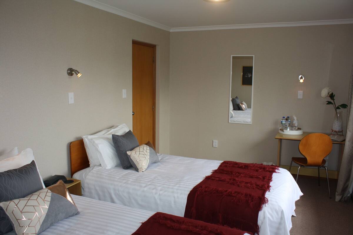 Ein Hotelzimmer mit zwei Betten, einem Schreibtisch und einem Stuhl.