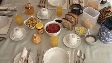 A breakfast table set with plates, bowls, and various food items.