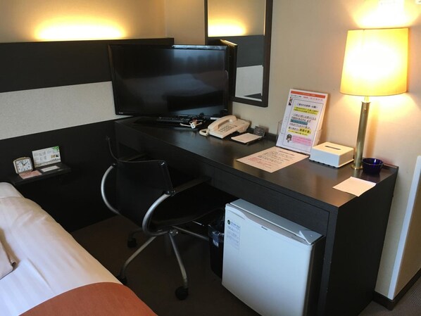 A hotel room with a bed, a desk with a computer, a telephone, a small refrigerator, and a lamp. - Ai Hotel Oyama (Oyama)