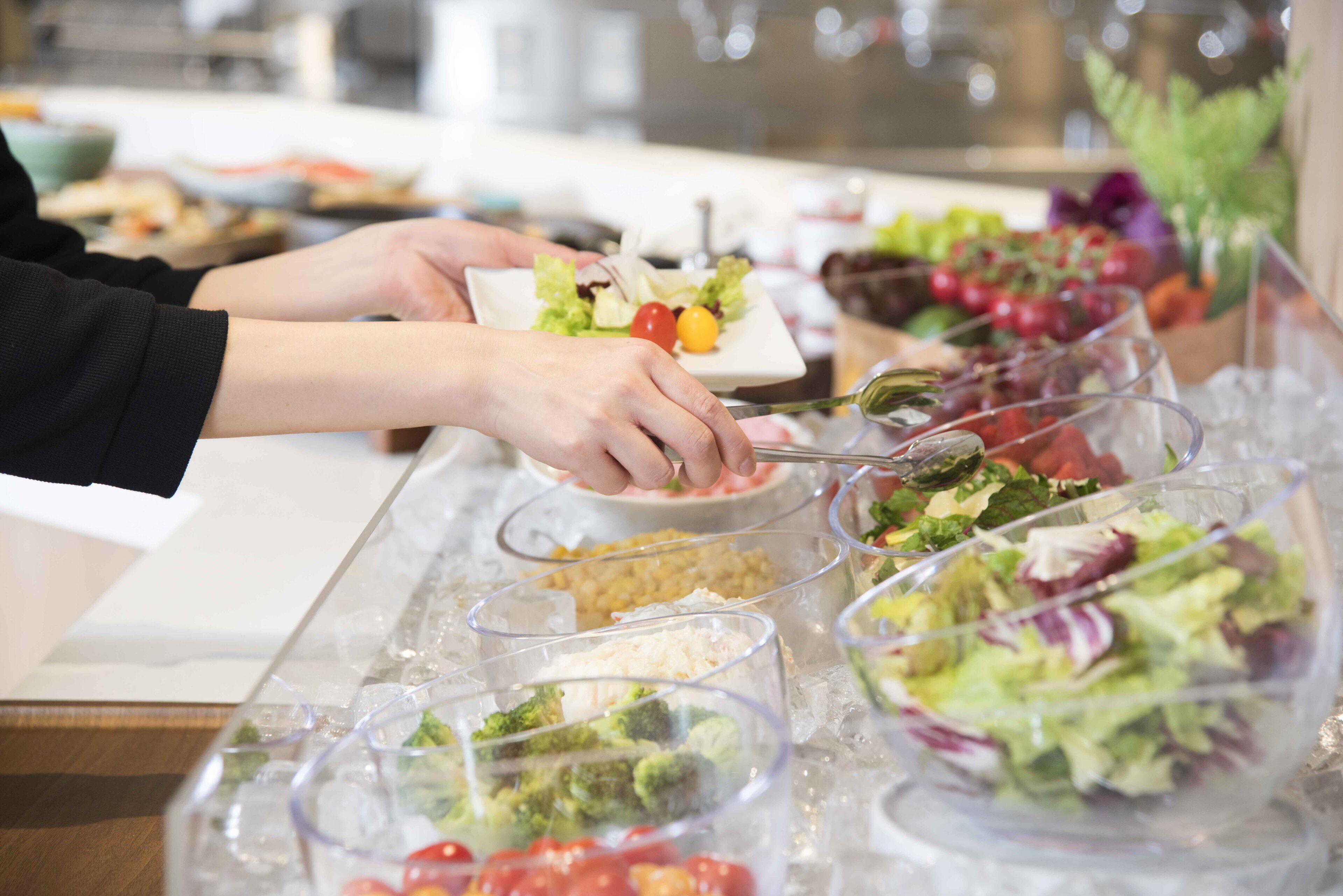 Un bufé con diversas opciones de comida, incluyendo ensaladas, verduras y otros platos.